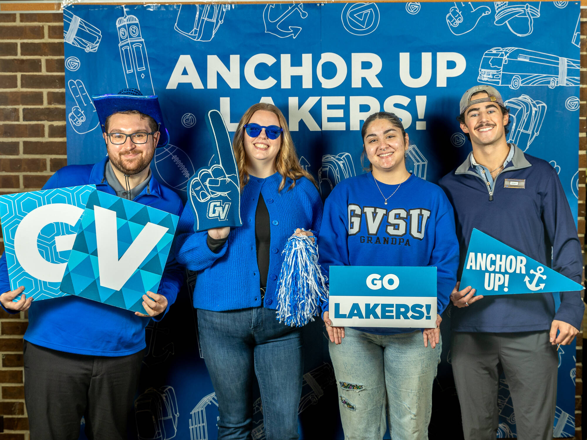 four individuals holding various gvsu signs